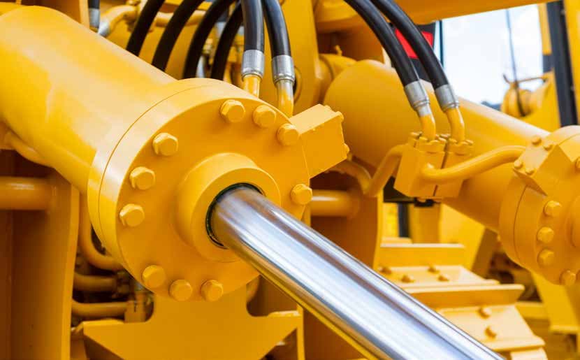 Gelbe Hydraulikzylinder und Hydraulikschläuche einer Baumaschine – Baumaschinenlack im Herstellerfarbton bei Farben Orth in Saalfelden