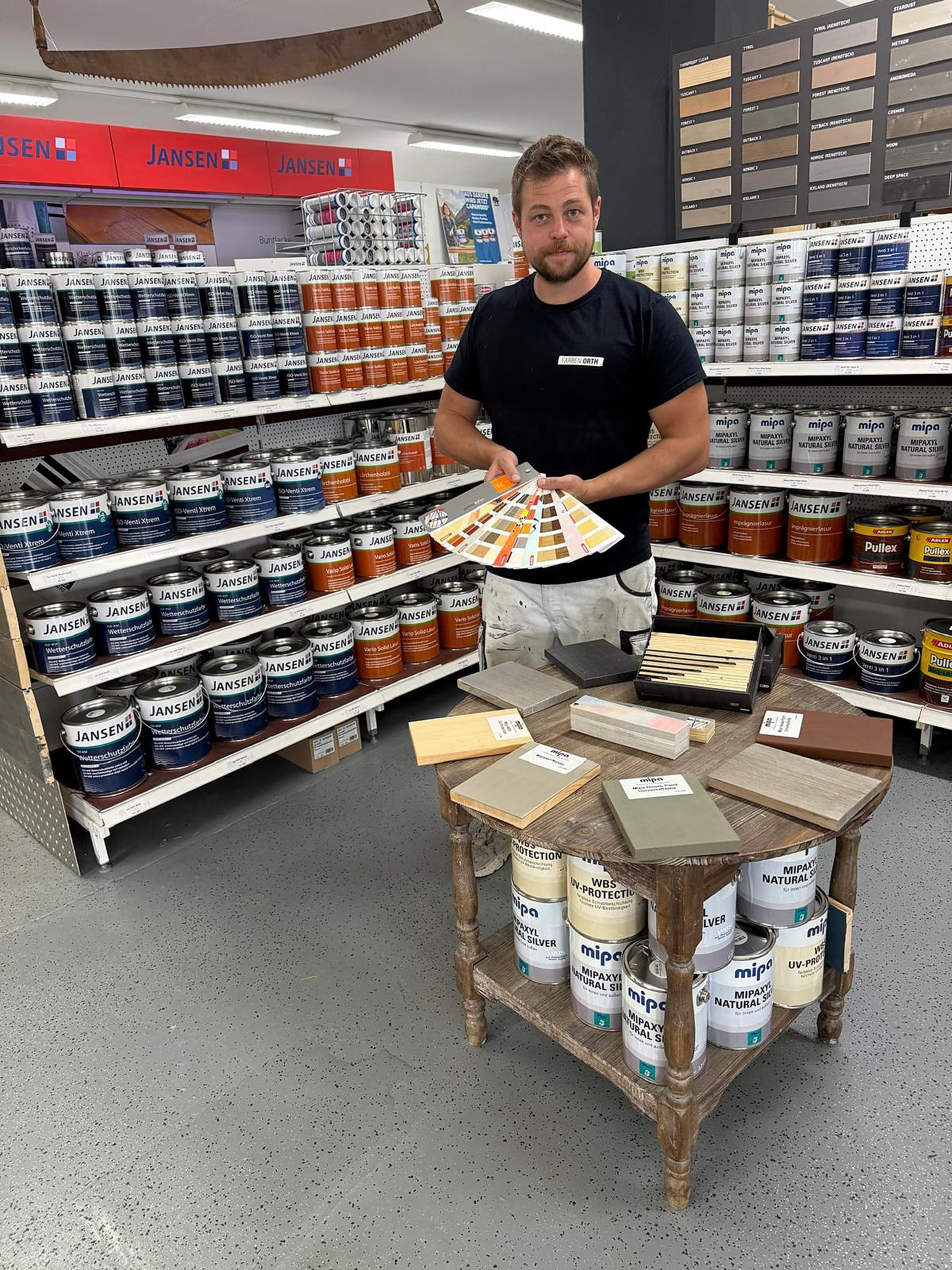 Jakob Orth im Fachmarkt mit Farbfächer und Holzmustern